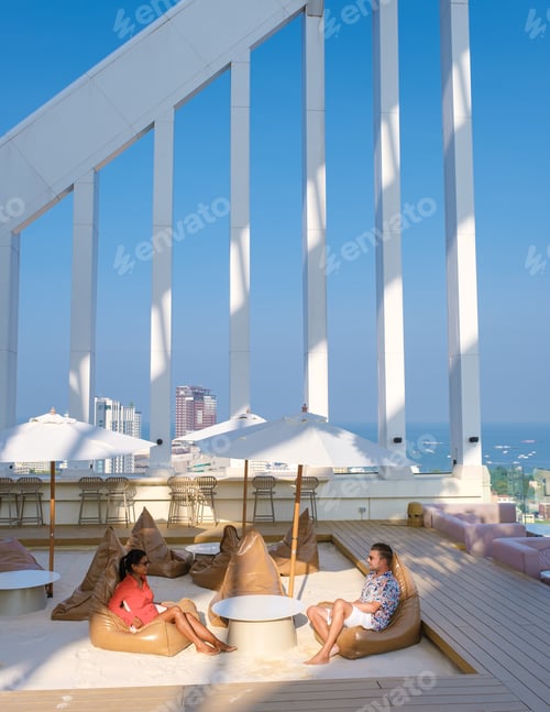 Vista previa: couple men and women having dinner during sunset at a rooftop restaurant looking out over the city