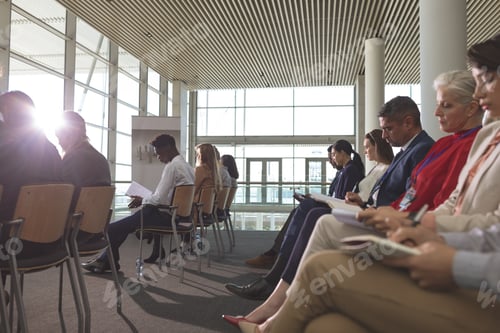 Preview: Side view of diverse business people writing on notepad in a business seminar in office building