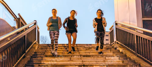 Preview: Women friends training running down stairs in town on sunset