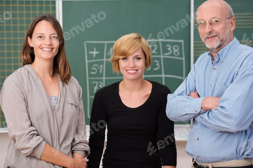 Preview: Group Of Three School Teachers With Confident Friendly Smiles Standing In Front Of A Class