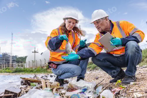 Preview: Two environmental engineers examine debris on a polluted shoreline