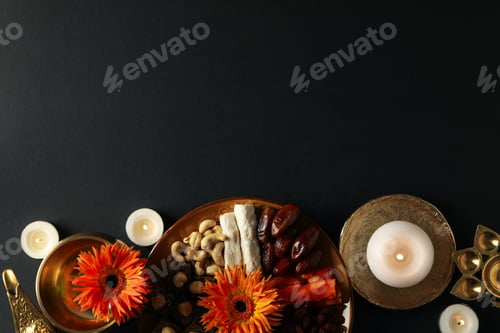 Preview: Copper dishes, plate with sweets and nuts, candles and flowers on black background, space for text