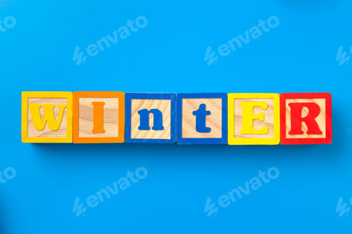 Preview: Winter. Wooden colorful alphabet blocks on blue background, flat lay, top view