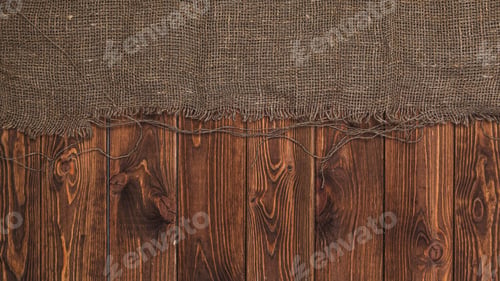 Preview: Old burlap fabric napkin on brown wooden background, top view