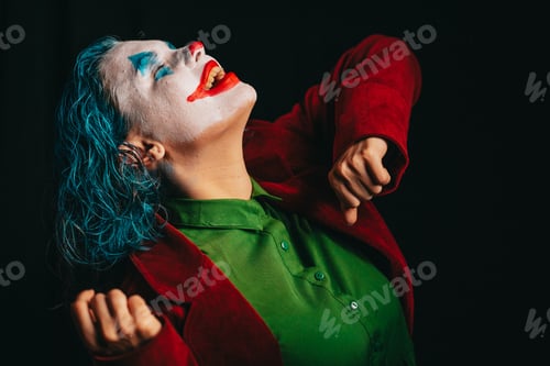 Vista previa: Make-up Joker with green hair for Halloween. Dancing. Close-up screaming face on black background.