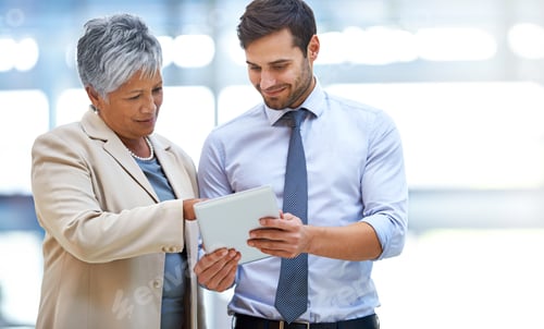 Preview: Shot of two business colleagues discussing work while standing with a digital tablet