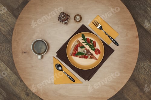 Preview: flat lay with arranged piece of pizza on plate, cup of tea and cutlery on wooden tabletop