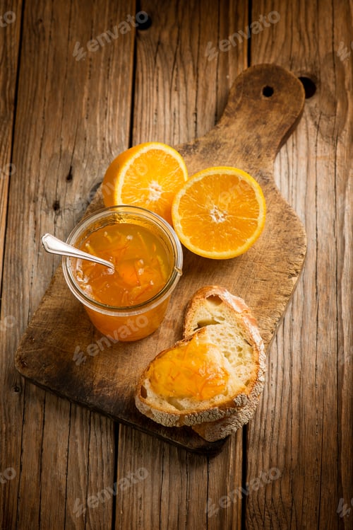 Preview: orange marmalade with bread over wooden background