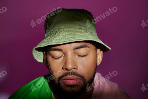 Vista previa: close up young man in green panama with purple sweatshirt tied on shoulders, closed eyes, fashion