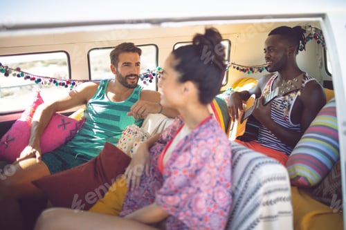 Preview: Side view of happy group of diverse friends having fun in a camper van at beach