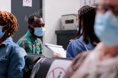Preview: Male patient with face mask talking to assistant