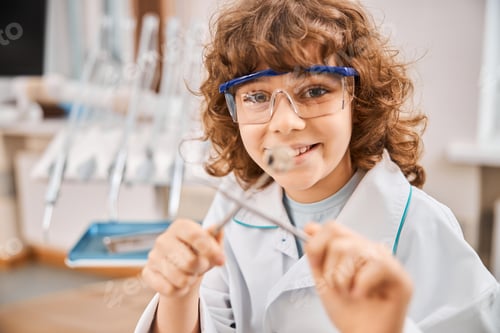 Preview: Cheerful child wearing dentist uniform and playing with tools