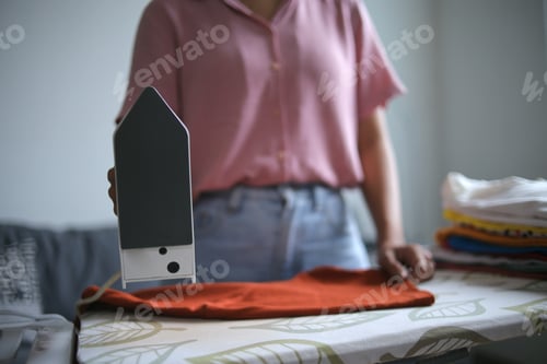 Preview: Unrecognized Woman Stand The Iron While Ironing Clothes On Board