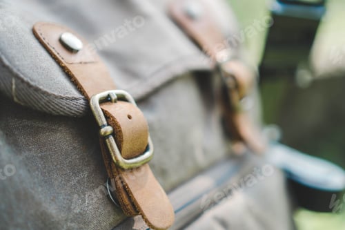 Preview: Closeup of a modern backpack with leather straps under the sunlight with a blurry background