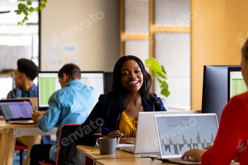 Preview: Happy casual businesswoman and diverse colleagues working using computers in office
