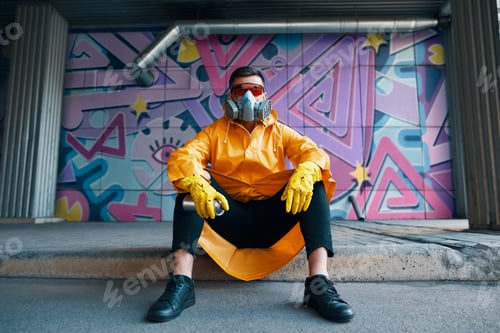 Preview: Graffiti painter rest near the wall with his paintings looking to camera