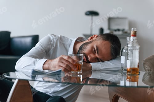 Preview: Life crisis. With whiskey. Upset young man drinker alcoholic is indoors
