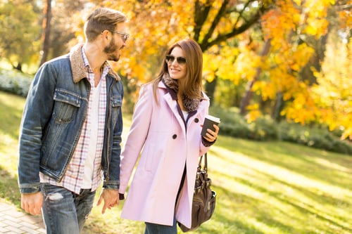 Preview: Young couple walking with coffee cups in the autumn park