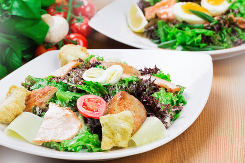 Preview: Fresh and colorful salad with greens, salmon, and toppings served on a wooden table with additional
