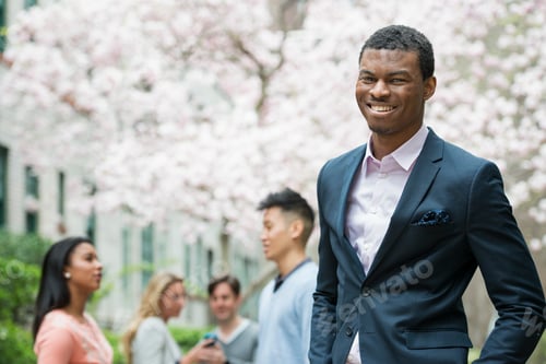Preview: A man in a suit, people in the background using cell phones.