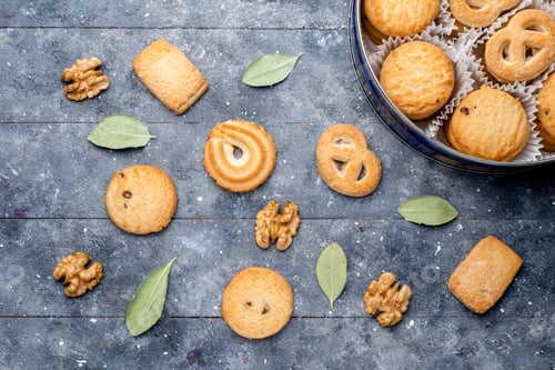 Preview: top view delicious cookies different formed inside round package with walnuts on the grey desk sugar