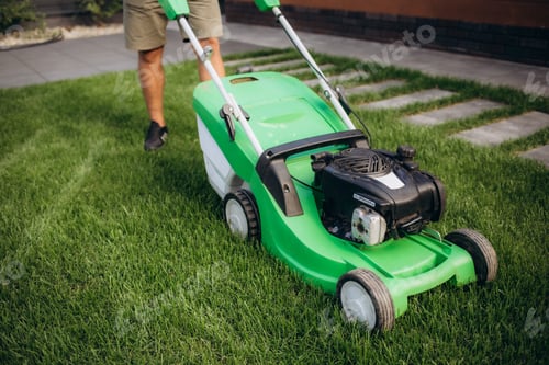 Preview: Lawn mover on green grass in modern garden. Machine for cutting lawns.