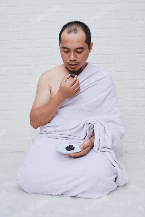 Preview: Muslim man sitting and eating dates fruits