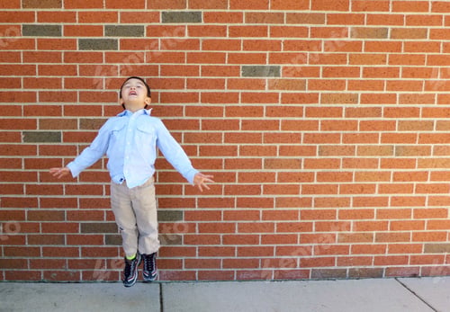 Preview: Boy jumping against brick background