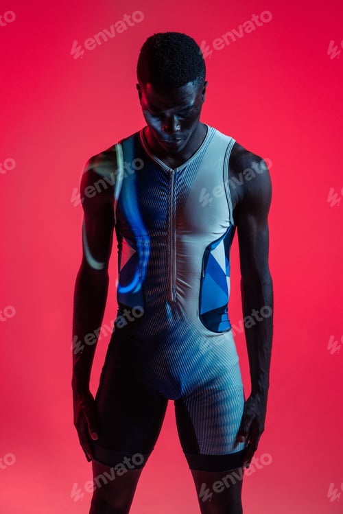 Preview: Muscular sportsman standing in red studio