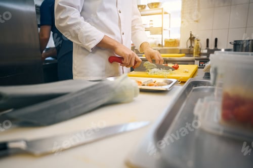 Preview: Cook cuts vegetables on a yellow cutting board