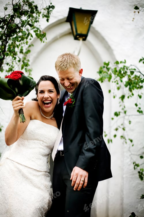 Preview: Cheerful bridegroom standing against building