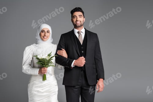 Preview: portrait of cheerful groom in suit standing muslim bride with wedding bouquet of calla lily flowers
