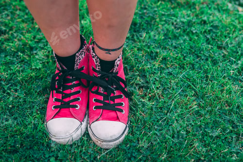 Preview: Girl in stylish pink sneakers standing on fresh green grass