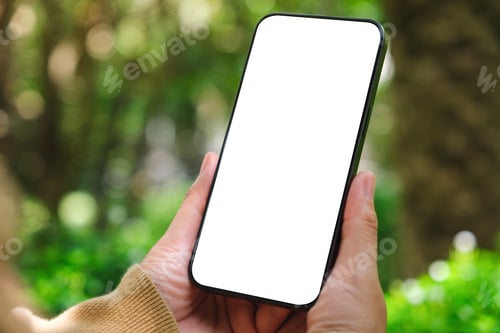 Preview: Mockup image of a woman holding mobile phone with blank white desktop screen in the outdoors