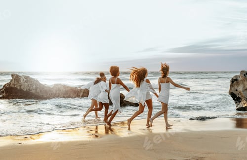 Preview: Happy young female friends having fun and celebrating hen party while running on the beach at the