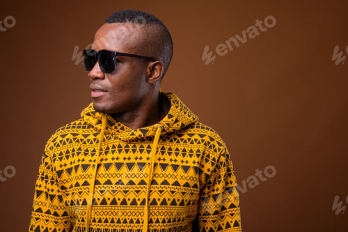 Preview: Studio shot of young African man against brown background