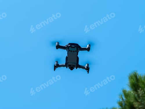 Preview: Image of a drone under the blue sky in full flight.
