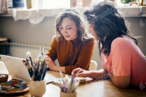 Preview: Two attractive young female employees discussing their business in workshop