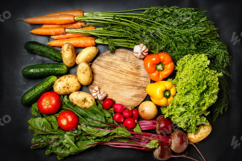 Preview: Frame made of fresh assorted vegetables on dark black background around wooden cutting board