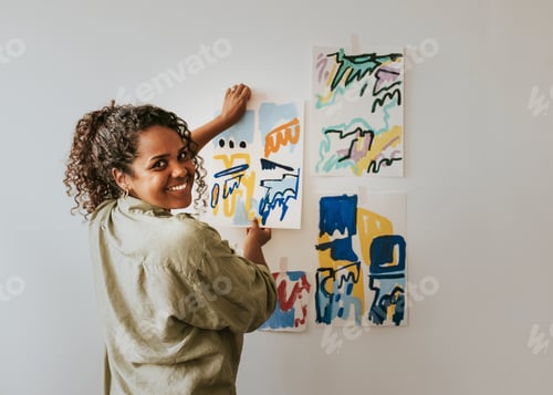Preview: Woman artist putting her abstract artwork on the mood board wall
