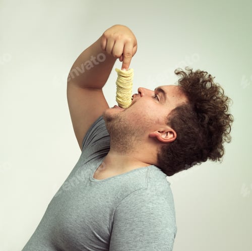 Preview: Studio shot of an overweight man shoving a stack of chips down his throat