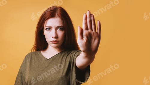 Preview: serious young woman making stop gesture with left hand