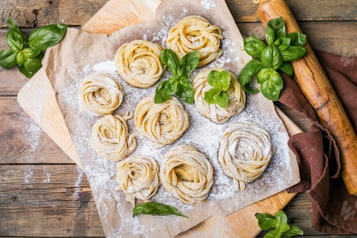 Preview: Pasta alluovo, Tagliatelle or fettuccine. Round balls of raw pasta on the wooden cutting board