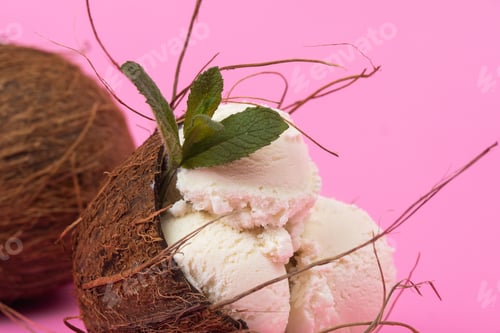 Preview: Vanilla ice cream balls in an empty coconut decorated with mint leaves on a pink background