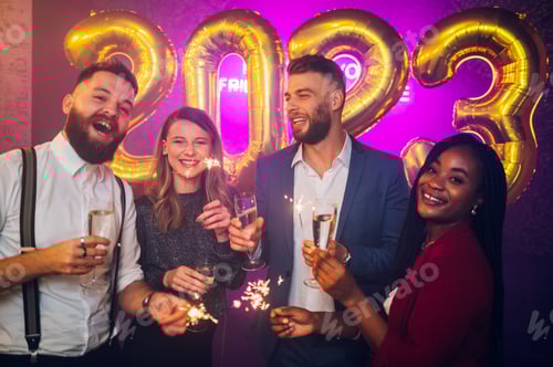 Preview: Multiracial friends celebrating new years eve with champagne and sparklers