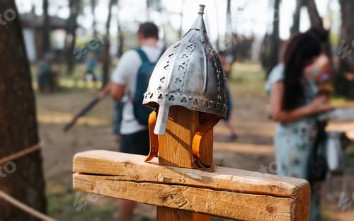 Preview: Close-up of a knight's steel protective helmet on a wooden cross, side view.