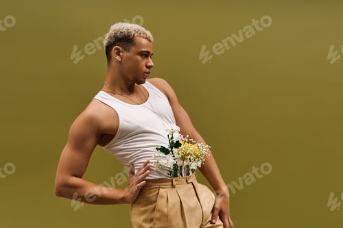 Preview: Young man radiates style in tank top, capturing beauty in a floral studio setting