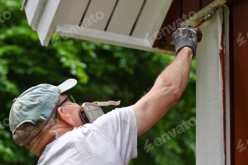 Preview: A man painting house exterior with white color