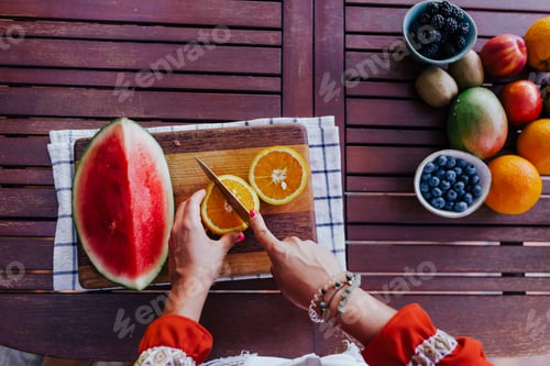 Preview: woman using mixer at home for healthy fruits juice, watermelon, blackberries and oranges