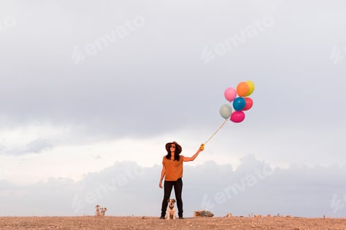 Preview: young beautiful woman with her dog outdoors. She is holding balloons. Love for animals concept